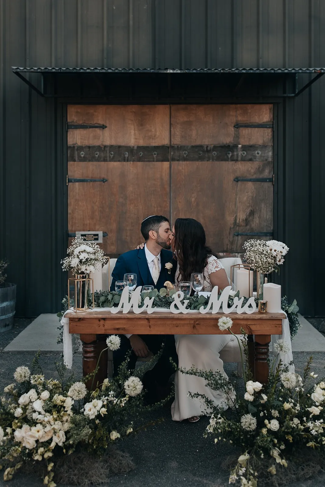 Wedding couple kiss in front of barn