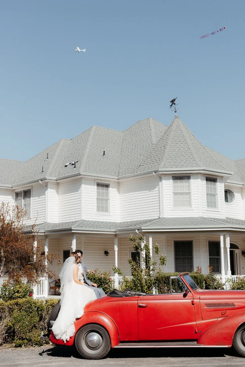 Bride and Groom in vintage car in front of Estate